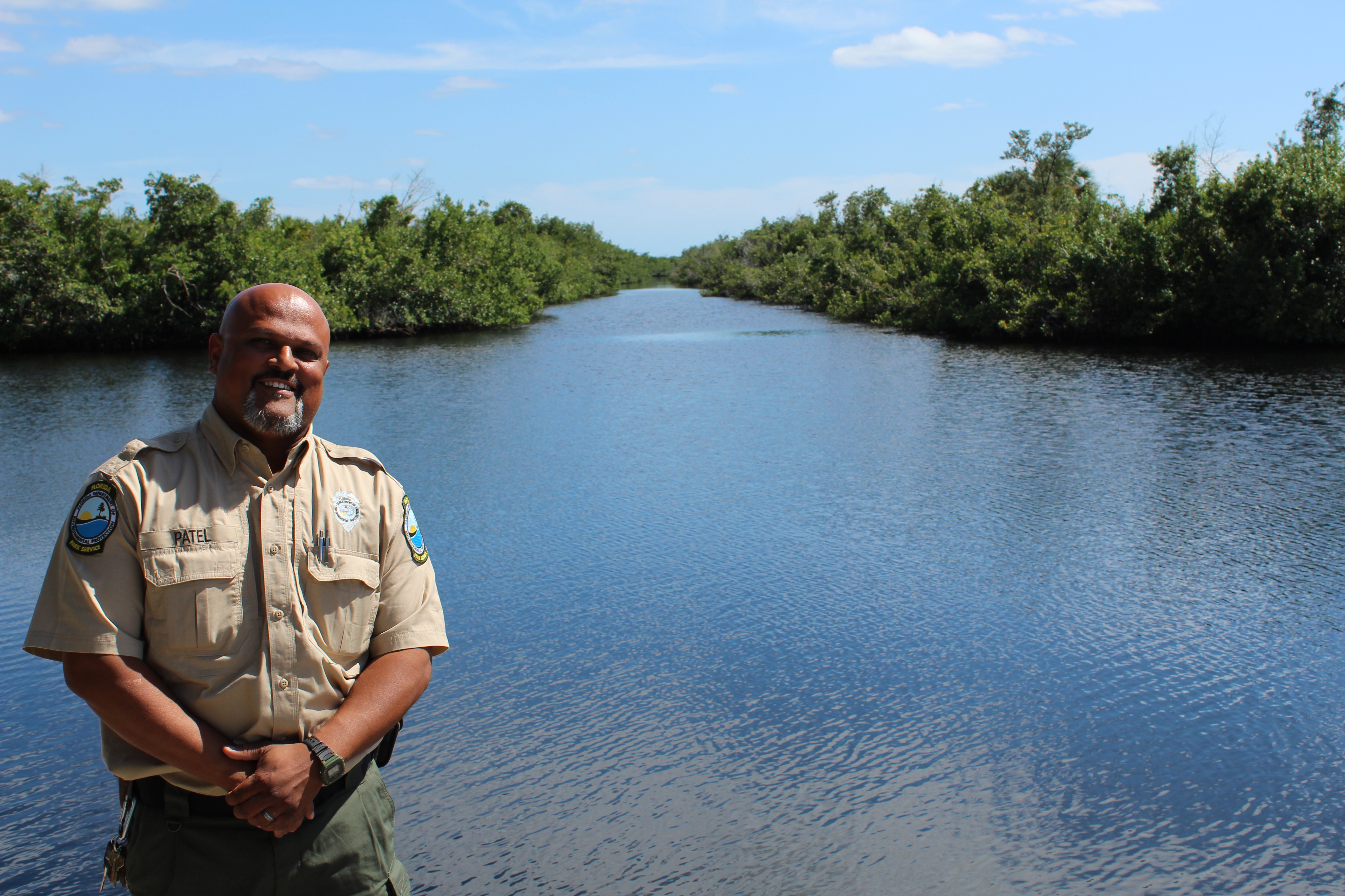 Maulik Patel stands on the seawall at Collier-Seminole State Park. Behind him, there is a view of the canal that connects to the Blackwater River. 