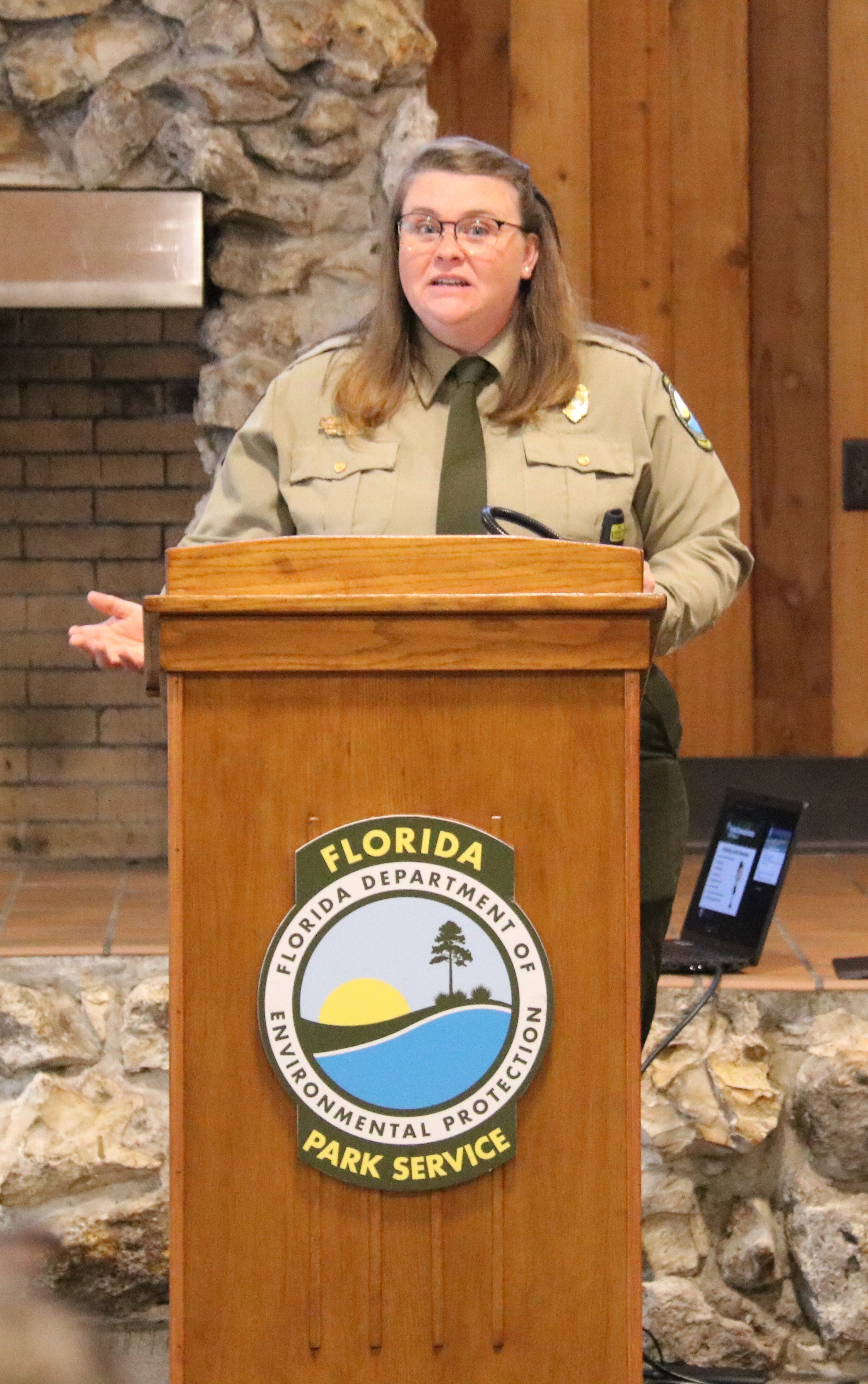 Heather Goston standing behind a podium, speaking to a group of assistant park managers and park managers.