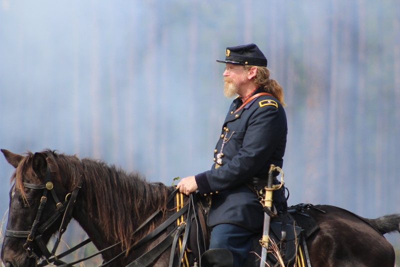a man in union dress rides a brown horse through smoke