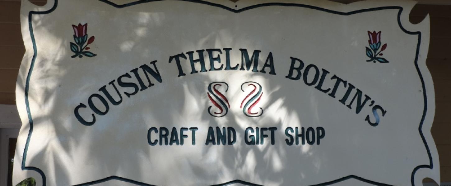 a sign above a porch reads "cousin thelma boltins craft and gift shop"