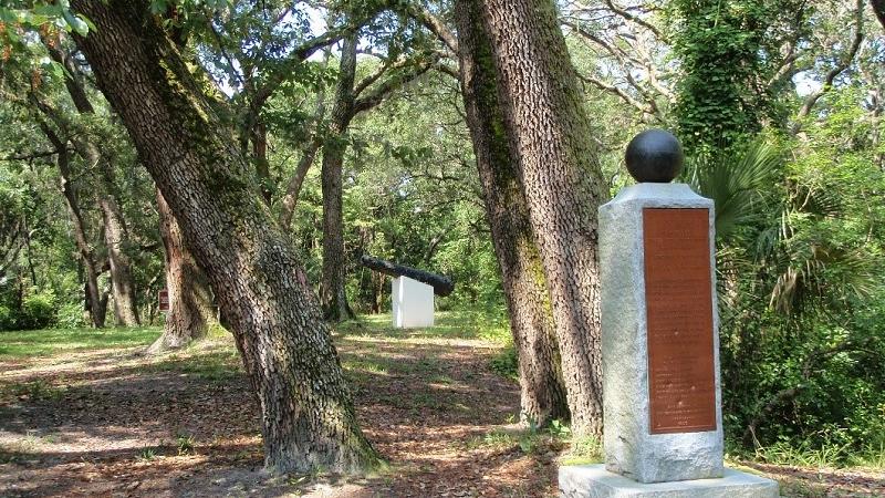a monument, trees, and cannon at yellow bluff fort historic state park
