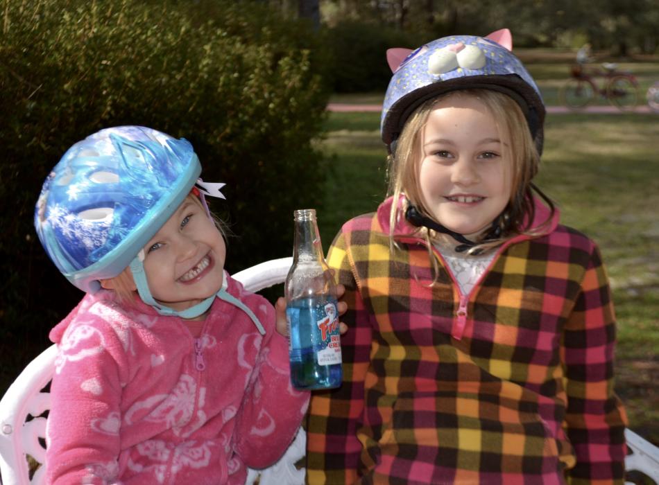 Two children preparing for a bike ride. They are wearing bicycle helmets.