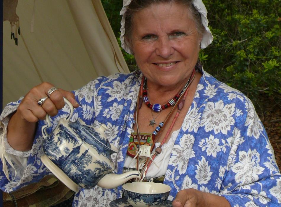 Norajean Miles dressed in period clothing holding a cup of tea.