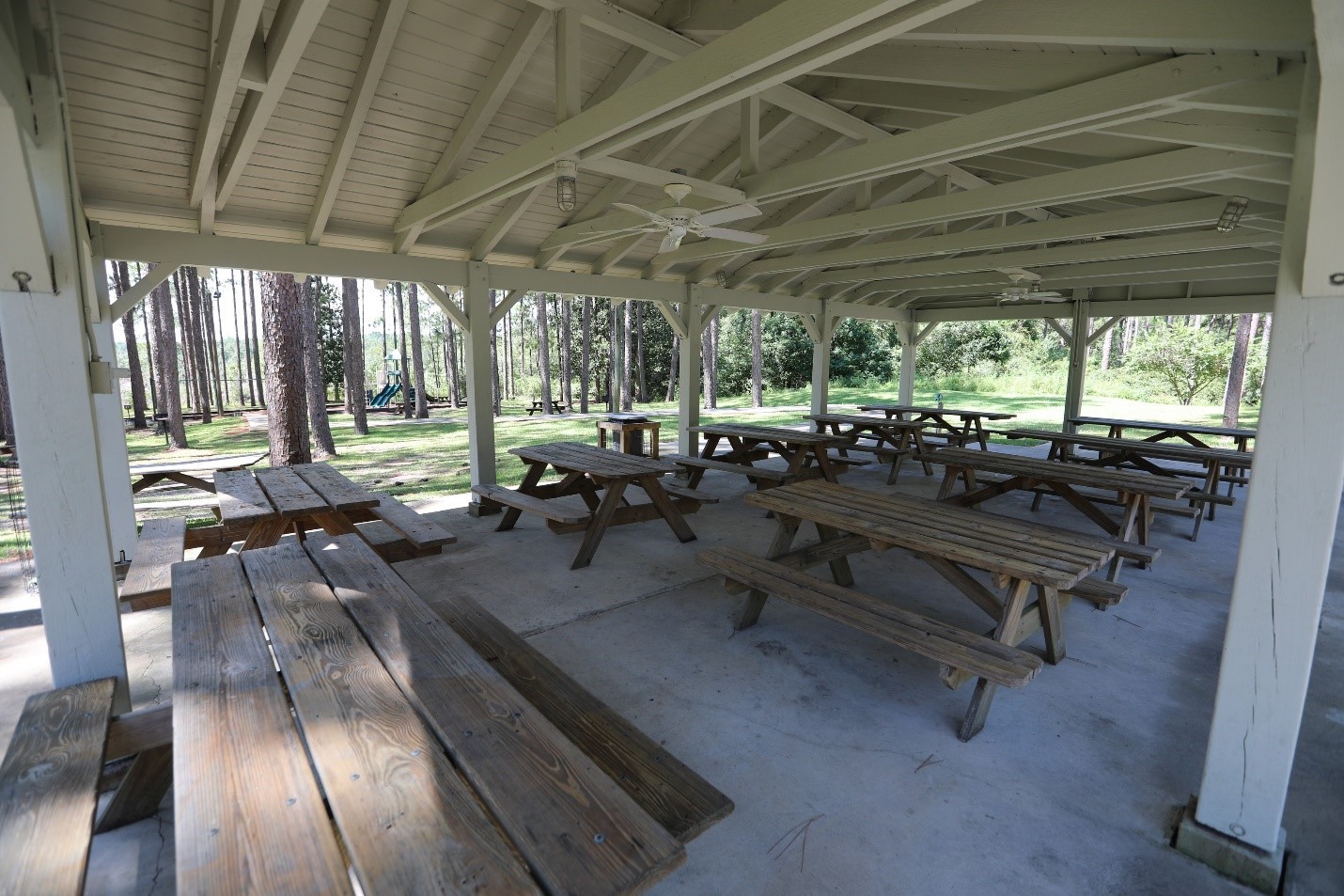A covered pavilion with picnic tables at Falling Waters State Park. A playground is located nearby.  