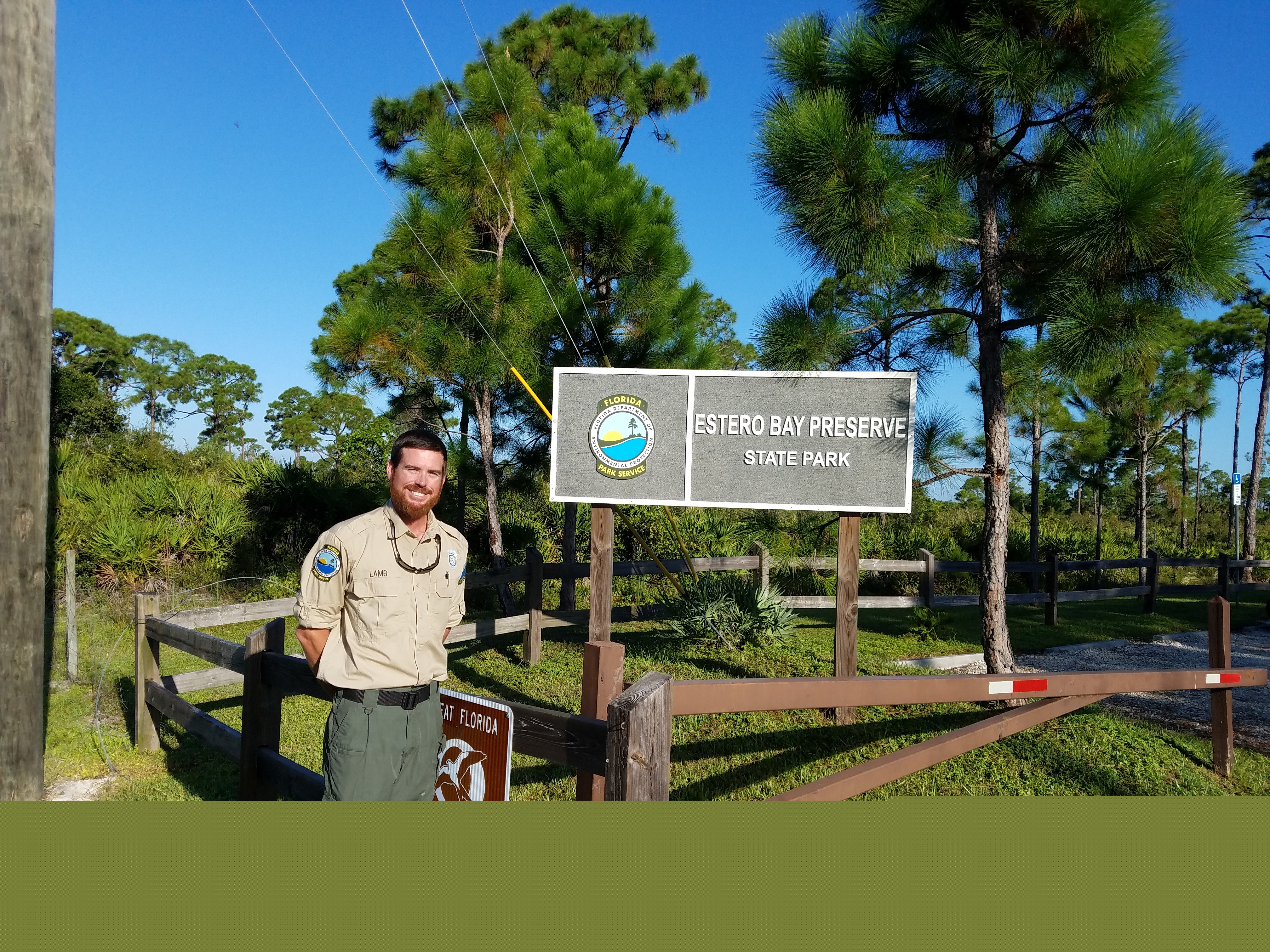 Justin Lamb poses with the park sign at Estero Bay Preserve State Park.