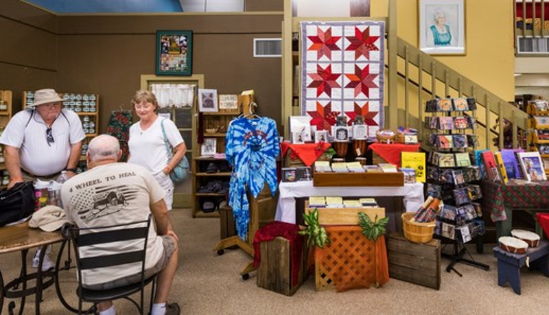 People shop in a small store with quilts and other crafts for sale