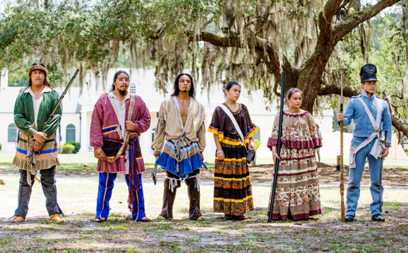 6 reenactors stand in a line in traditional Seminole and Army dress