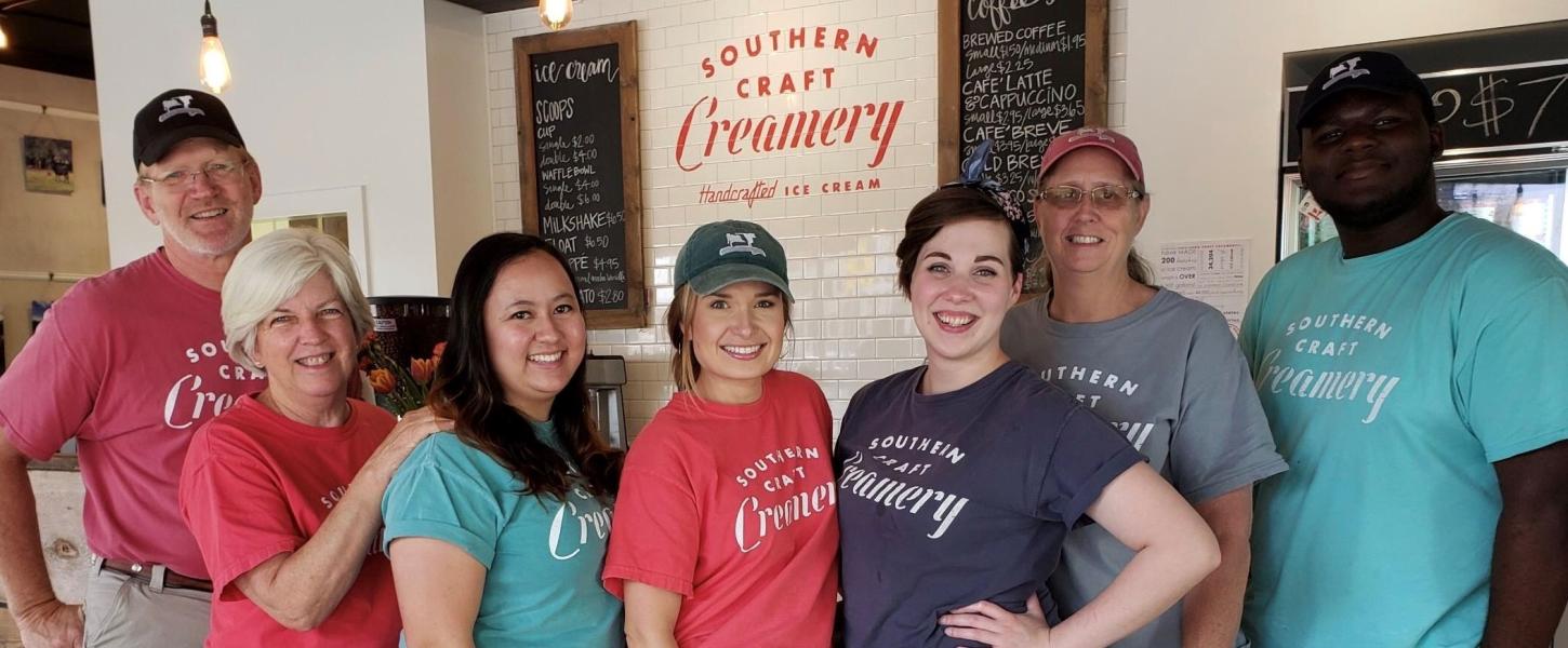 Seven Southern Craft Creamery staff members and owners stand in front of the bar at the shop. 