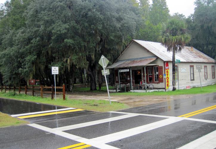 a small store sits on the intersection of a road and a paved bike path