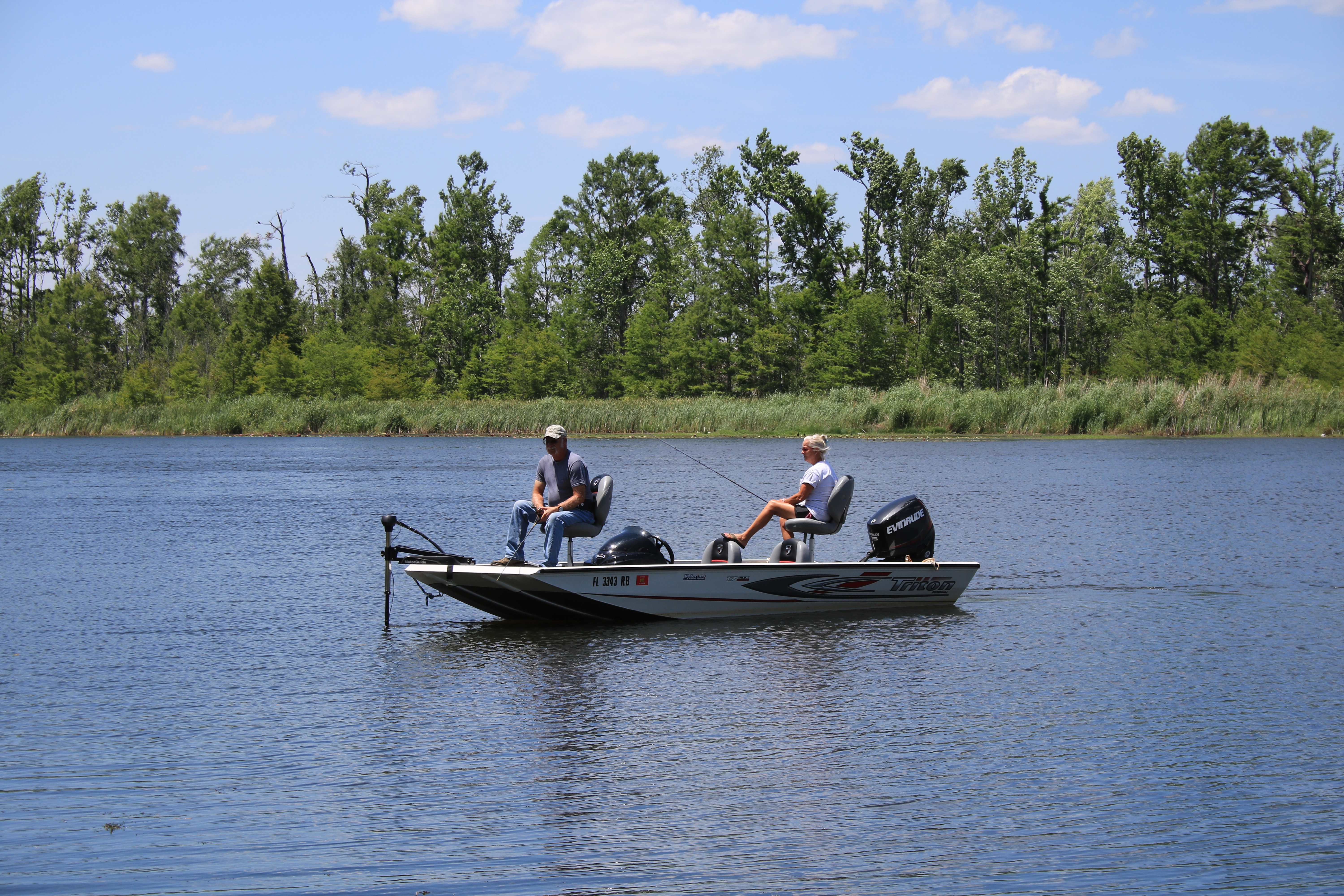 A view of a couple fishing in the lake from their boat.