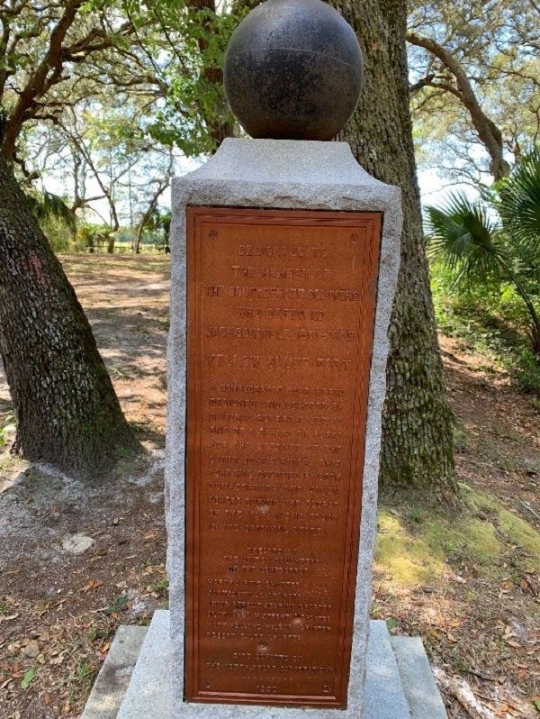 a stone monument with text, mounted by a cannon ball