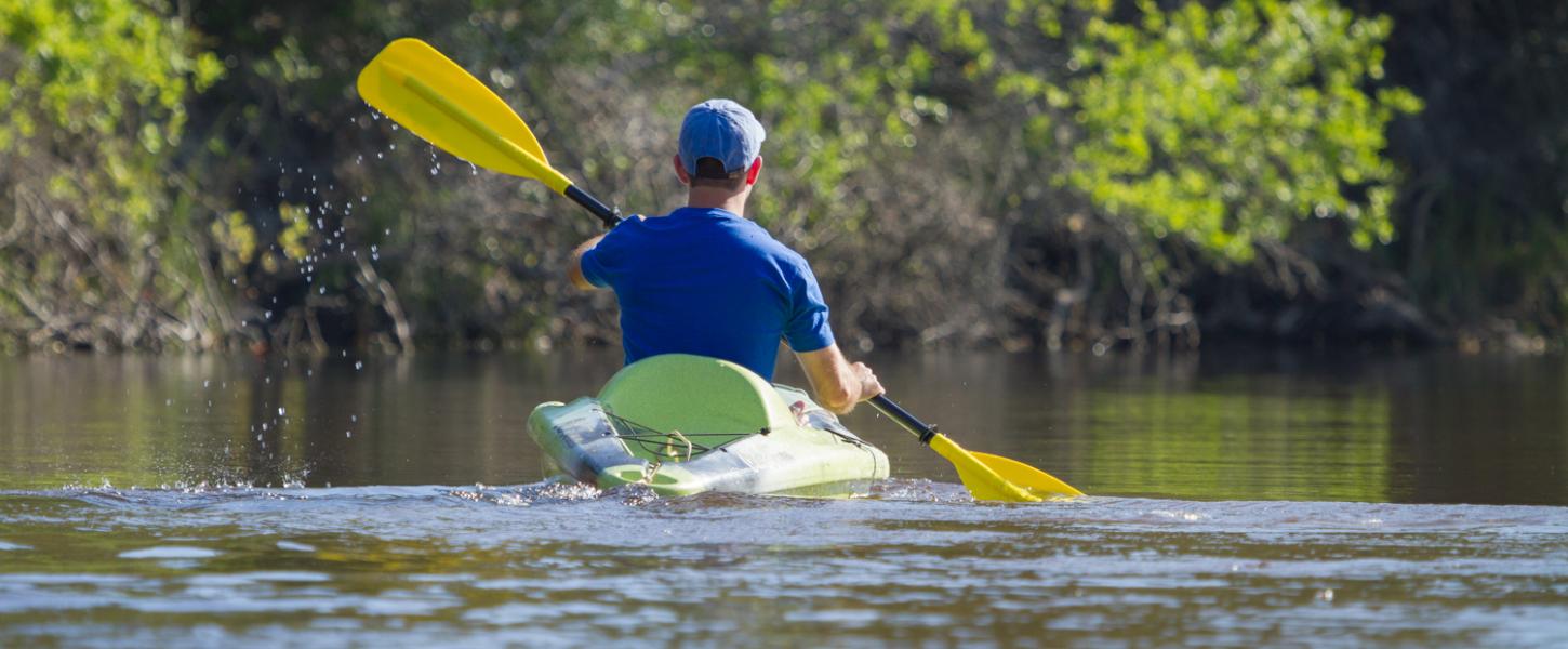 Man glides through water on green kayak. 