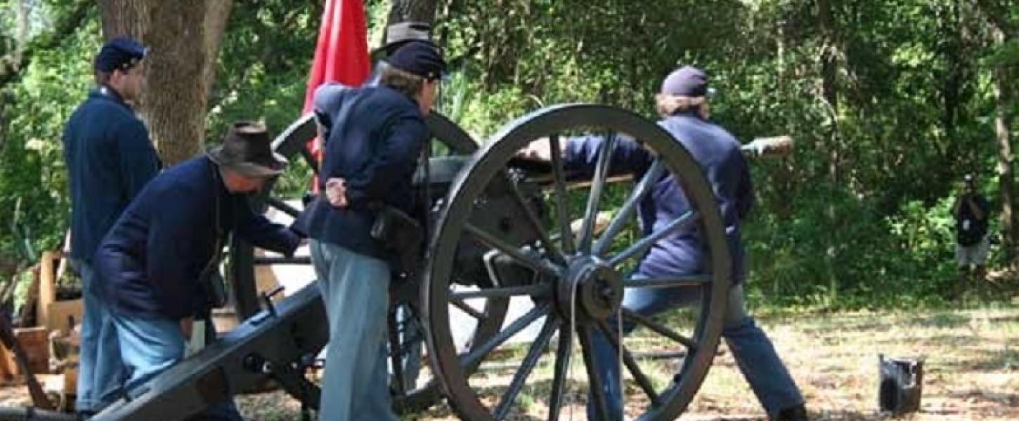 three reenactors dressed as union soldiers load a cannon