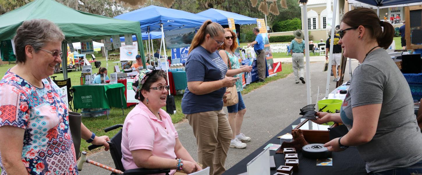 A state park volunteer at a booth, speaking with guests.