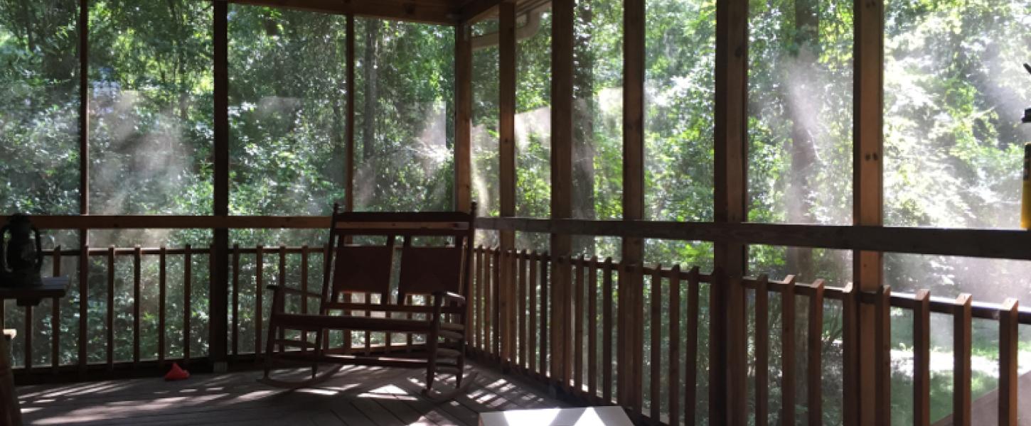 Image of the porch of a cabin with a rocking chair and cornhole board  at Suwannee River State Park.