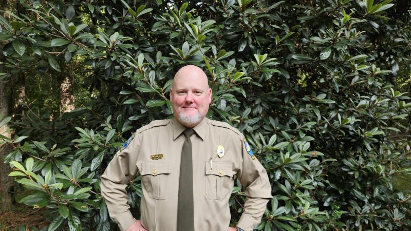 Park manager Brooke Doran, uniformed, in front of loquat trees.