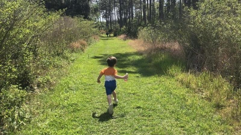 A young boy skips along the grassy trail.