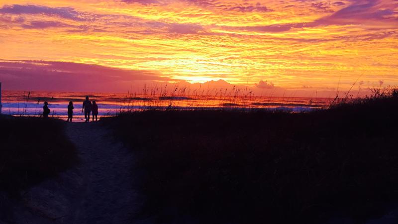 Image of four people silhouetted by the sunrise over the ocean at Little Talbot Island State Park.