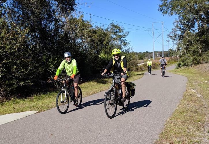 Three cyclists ride along a paved trail. 