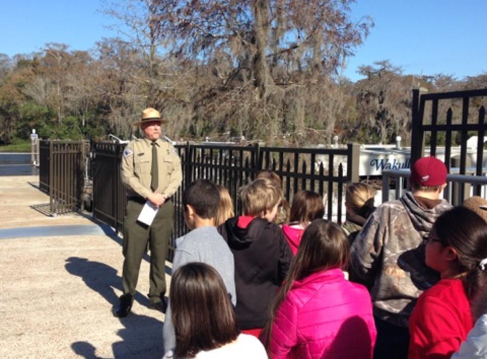 A group of children standing in a group, listening to a park ranger.