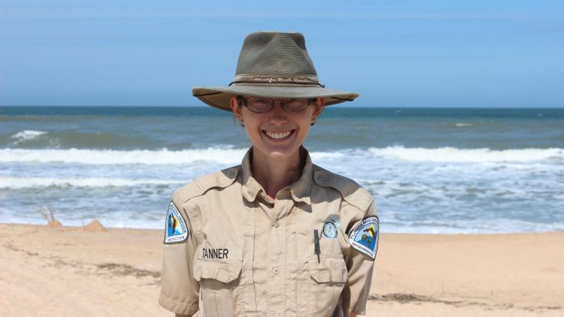 Park Ranger Jodi Tanner smiling at the camera with the ocean behind her