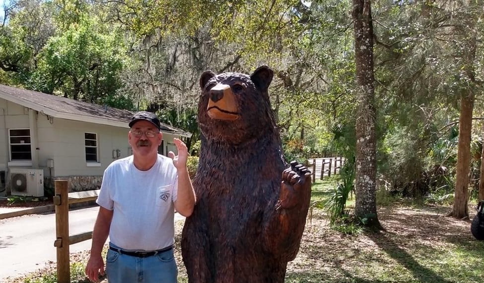 Dennis Bryant poses with a bear statue at the park.