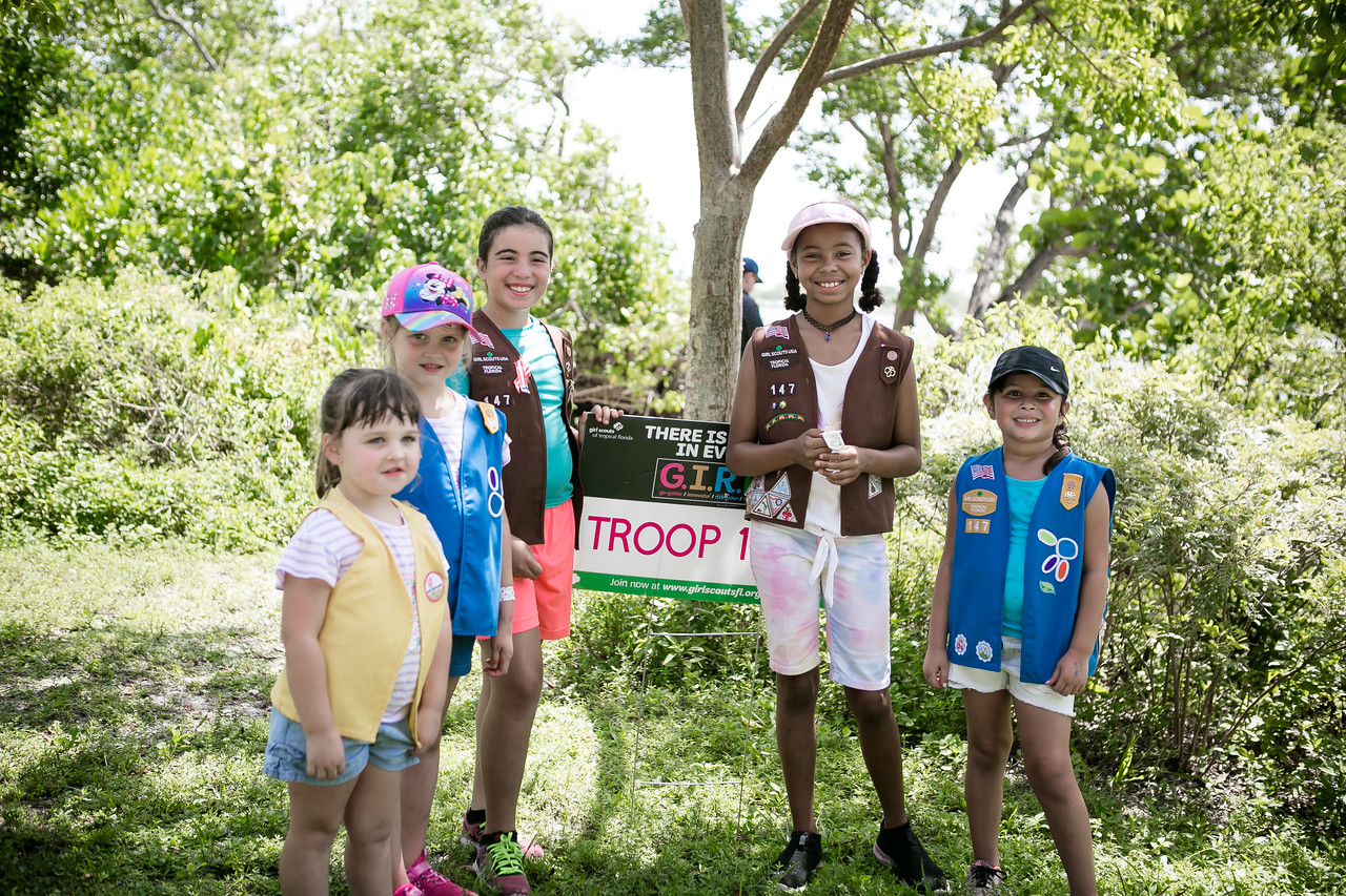 Girl Scouts hold up troop sign. 