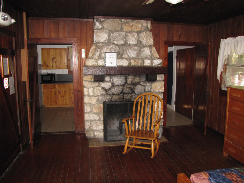a stone fireplace with a rocking chair in a wooden cabin