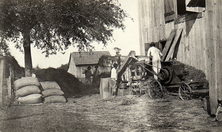 Threshing and bagging oats at a barn