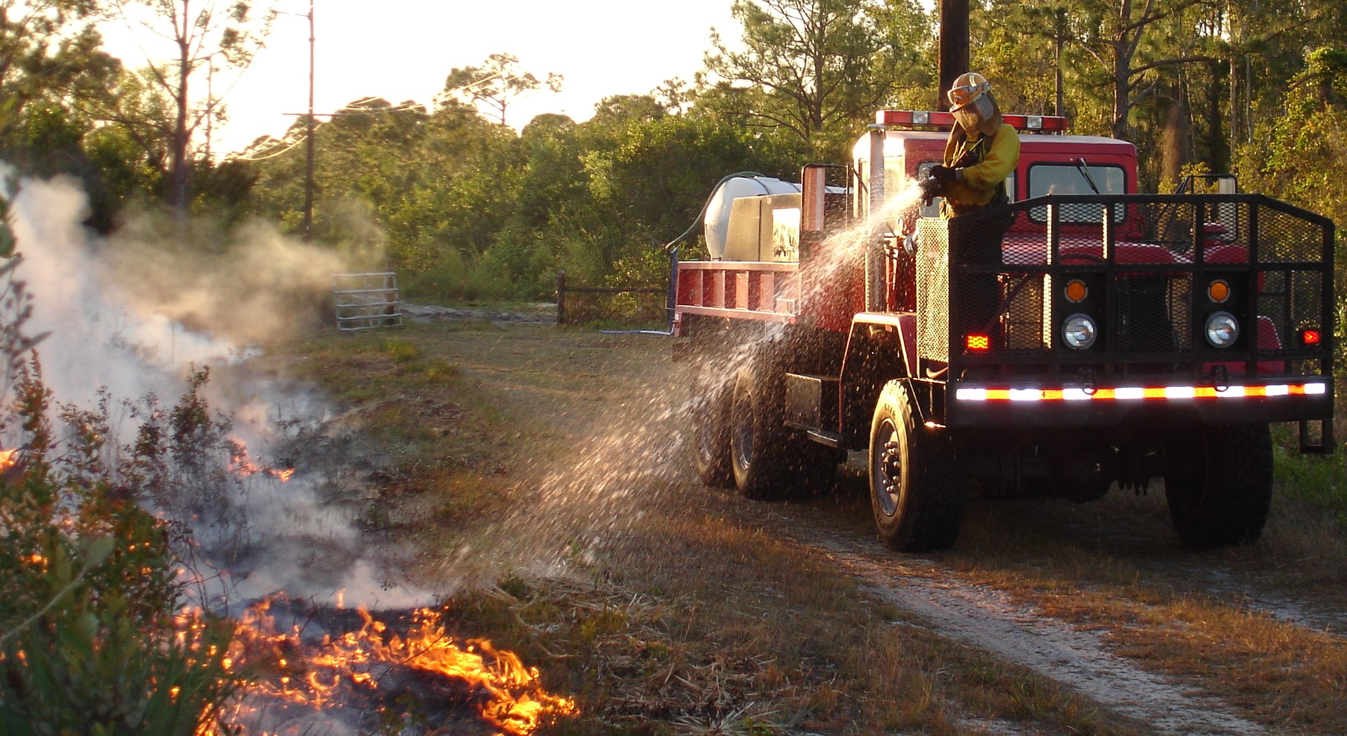 A fire expert spraying water on a prescribed burn.