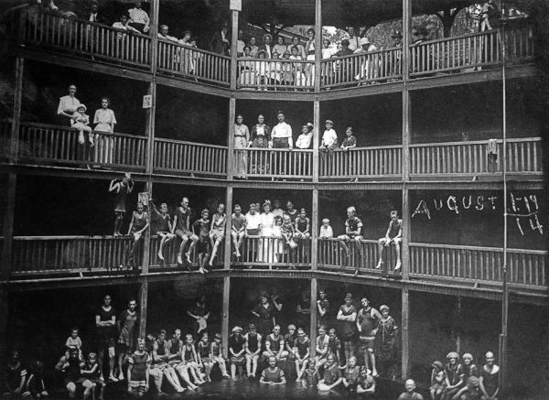 antique photo showing people standing in bathing suits on 4 floors of a building