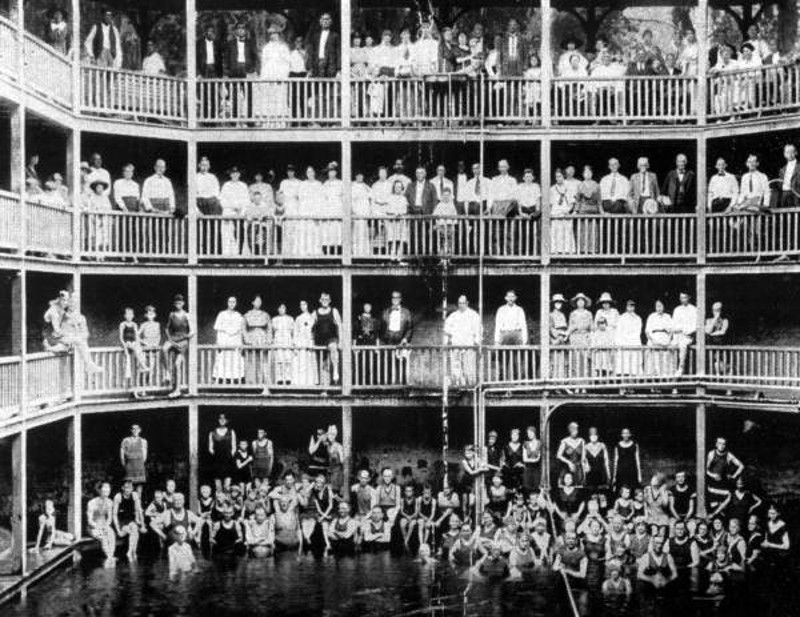 an old photograph showing many people standing in a multi-level bathhouse