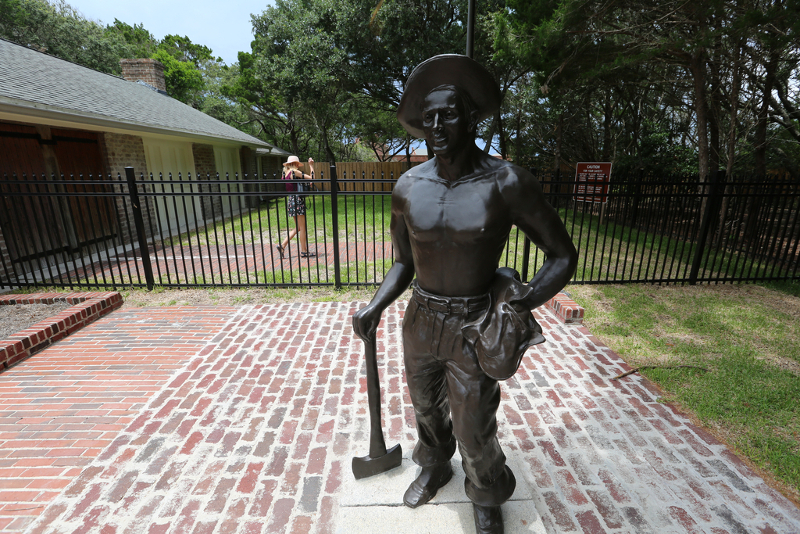 statue of a man standing with an ax outside iron gates at fort clinch.
