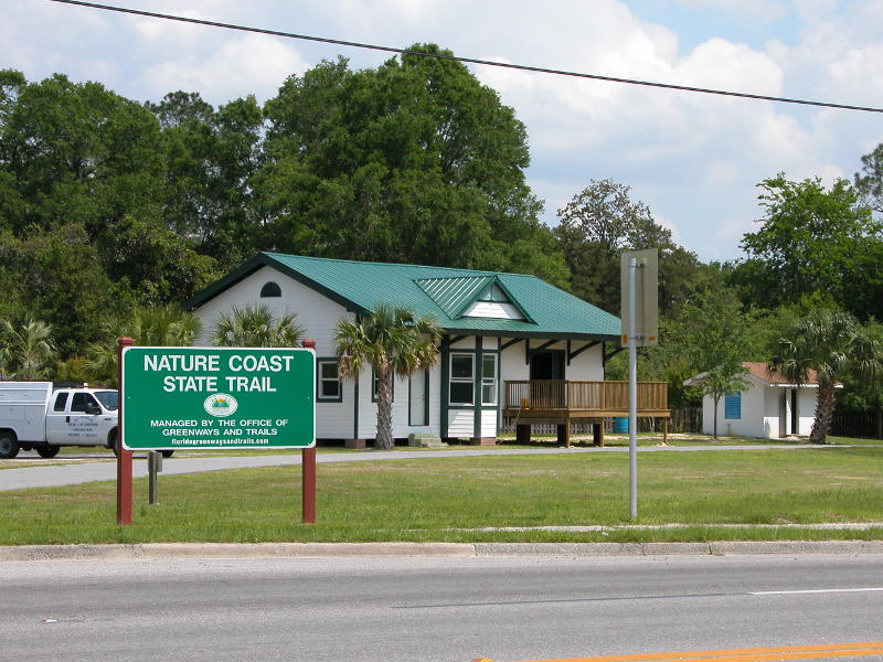 a green and white building with a green sign saying "nature coast state trail"