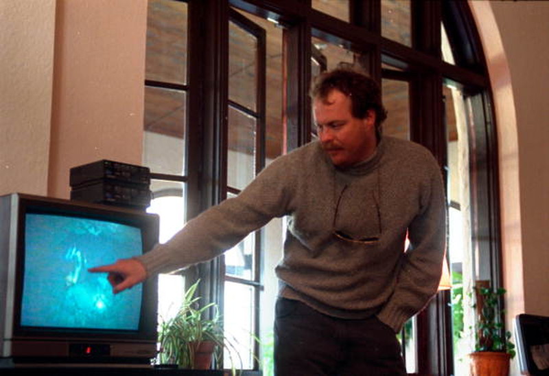 a man points to an image of a diver on a tv