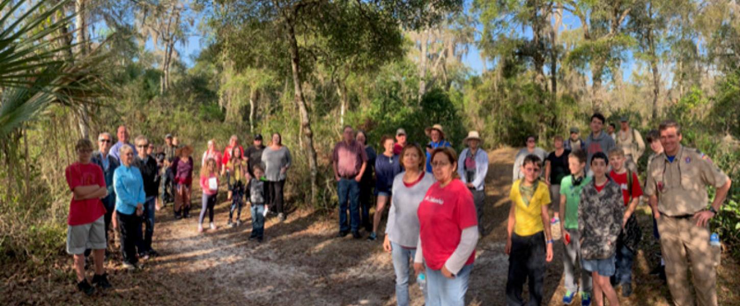 a large group of people waits to go on a guided hike on a trail