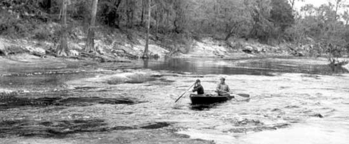 A historical photo of two paddlers in a canoe in Big Shoals. 
