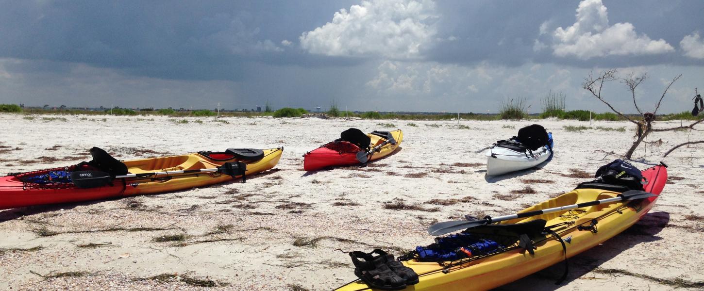 3 kayaks sitting on the shore of the beach.
