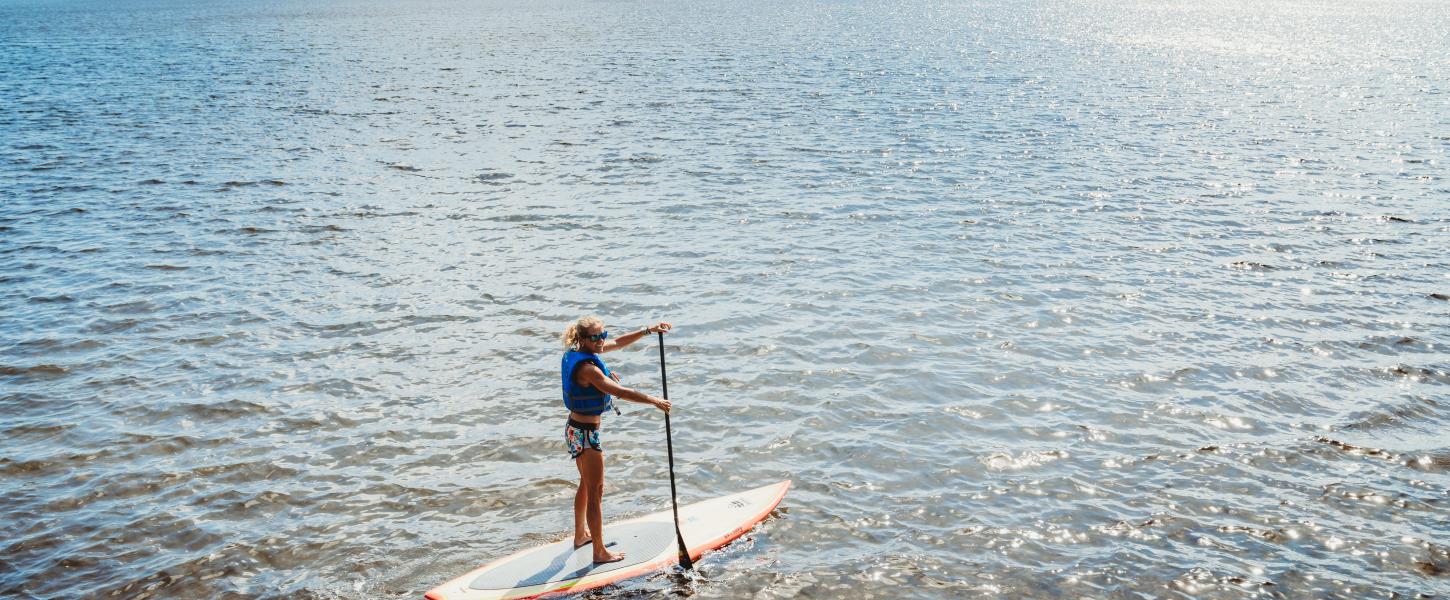 A person paddles a stand up paddle board.
