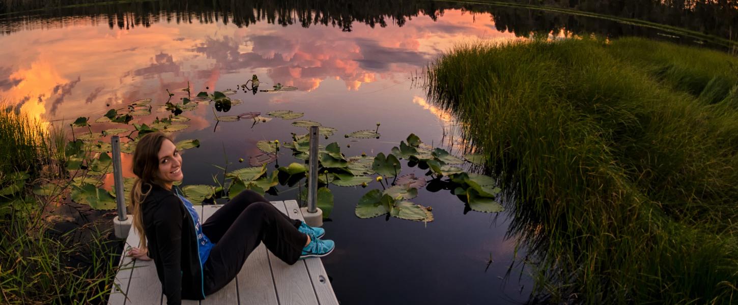 A person sitting on a dock on the edge of a lake.
