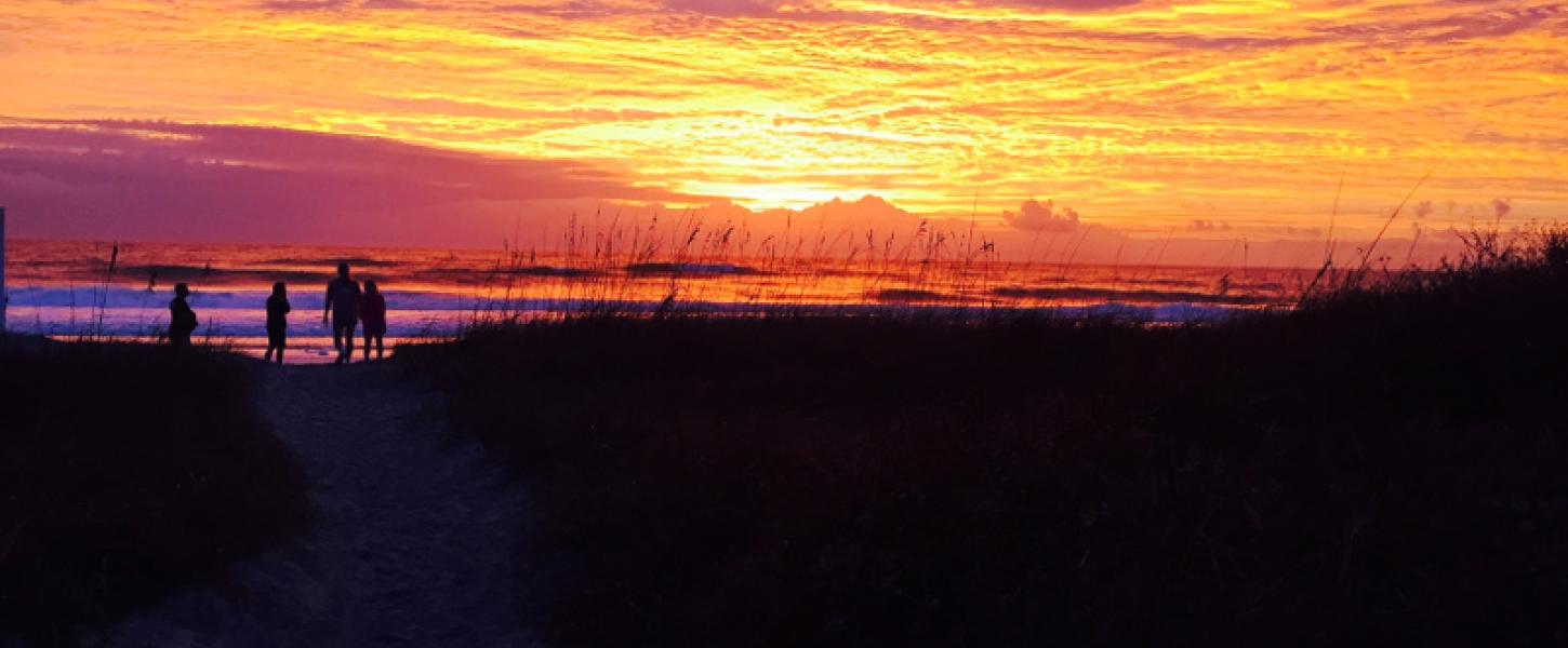 Image of four people silhouetted by the sunrise over the ocean at Little Talbot Island State Park.