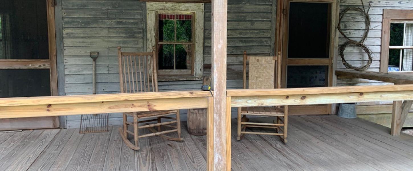 Two rocking chairs sits on the porch of a wooden cabin