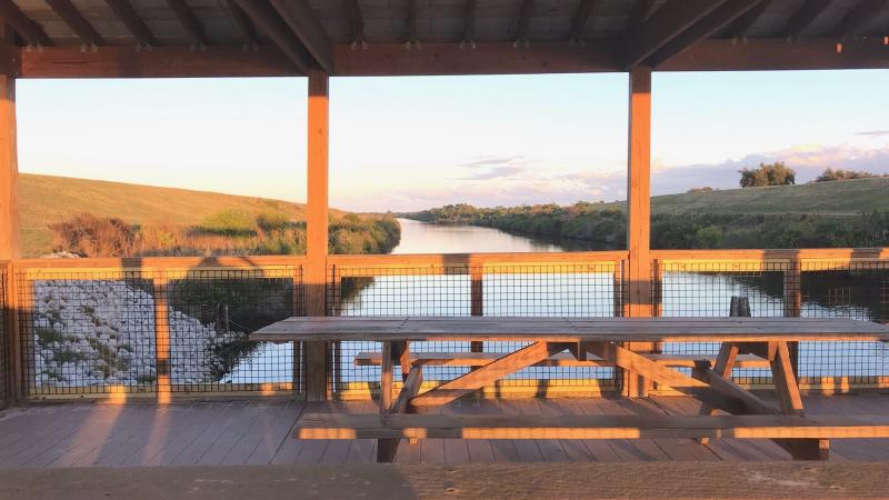 Wooden outlook that has wooden picnic tables during sunset