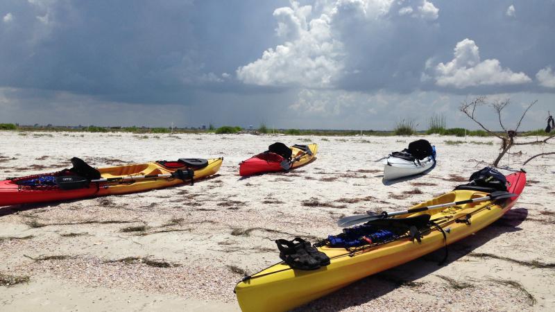 3 kayaks sitting on the shore of the beach.