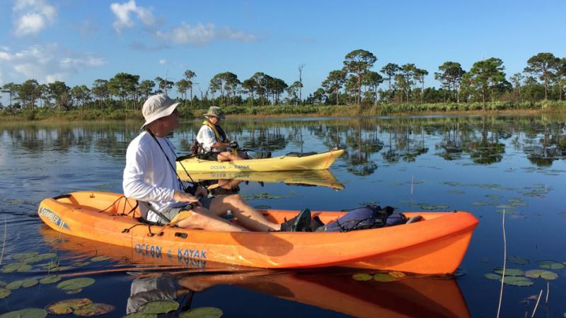 A male visitor resting in a kayak on a freshwater marsh.