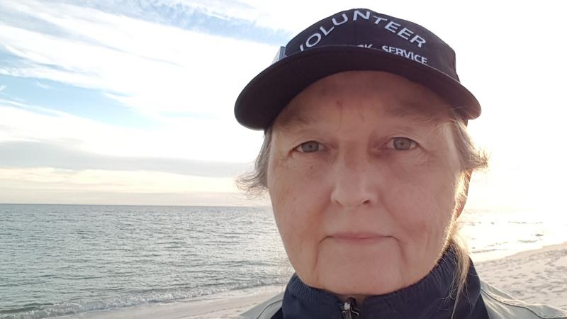 Volunteer Laura Junior proudly wears volunteer hat while walking the beach at Perdido Key. 