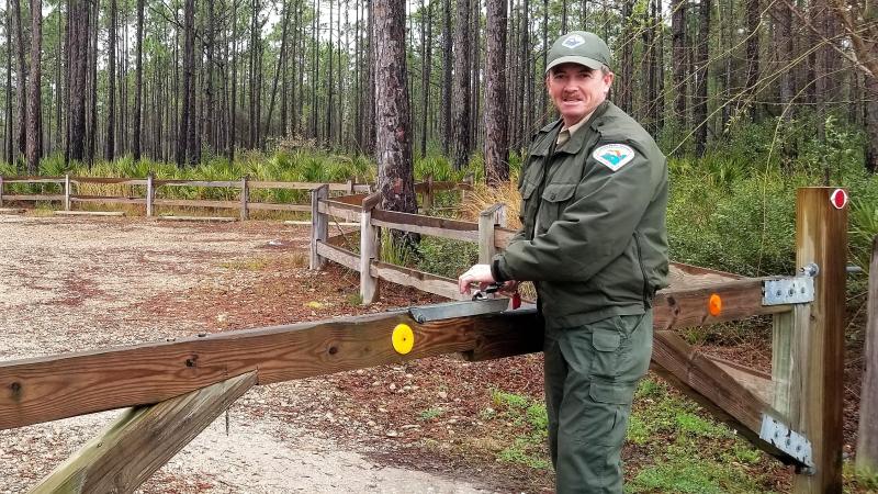 Scott Hoxie standing by a gate in his ranger uniform.