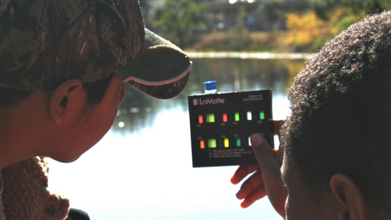 Two boys looking at a water testing device.