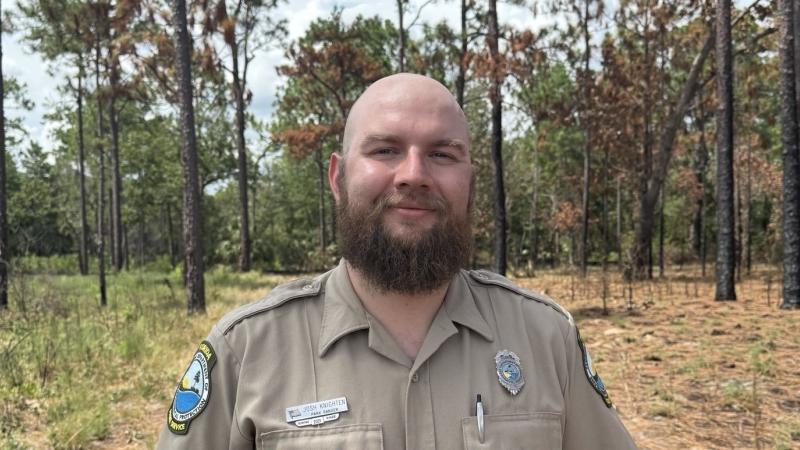 Josh Knighten standing in front of a forest.