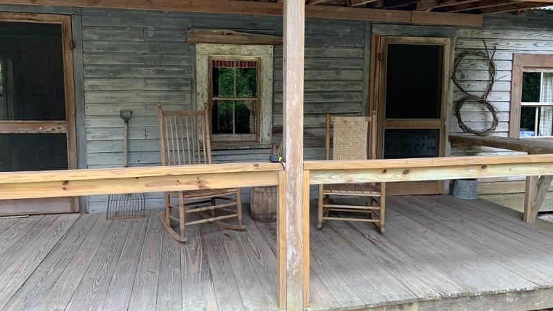 Two rocking chairs sits on the porch of a wooden cabin